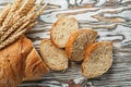 Sliced bread ripe rye ears on wooden surface Royalty Free Stock Photo
