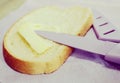 Sliced bread spread with butter or margarine and a knife