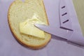 Sliced bread spread with butter or margarine and a knife