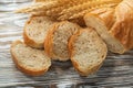 Sliced bread wheat ears on wooden surface Royalty Free Stock Photo