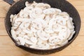 Sliced button mushrooms on old frying pan on rustic table Royalty Free Stock Photo