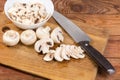 Partly sliced button mushrooms and kitchen knife on cutting board Royalty Free Stock Photo