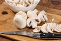 Partly sliced button mushrooms and kitchen knife on cutting board Royalty Free Stock Photo