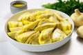 sliced canned artichoke hearts arranged in a white bowl