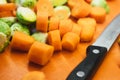 Sliced carrots and halved brussel sprouts on a vegetable chopping board with a knife Royalty Free Stock Photo