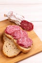 Sliced cereal bread and slices of dried Italian sausage on a wooden cutting board. Simple food for a snack at home. Selective Royalty Free Stock Photo