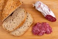 Sliced cereal bread and slices of dried Italian sausage on a wooden cutting board. Simple food for a snack at home. Selective Royalty Free Stock Photo