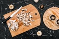 Sliced champignon mushrooms on a wooden board. Knife and garbage from food. Ingredients for cooking. Top view against a Royalty Free Stock Photo