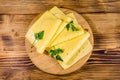 Sliced cheese and parsley on a wooden cutting board. Top view