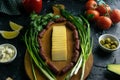 Sliced cheese on a wooden board, around the ham, green onions, tomato, souce, olives, lemon, spice, dill Royalty Free Stock Photo