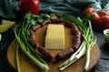 Sliced cheese on a wooden board, around the ham, green onions, tomato, souce, olives, lemon, spice, dill Royalty Free Stock Photo