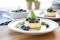 sliced cheesecake on white plate with blueberries on top