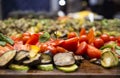 sliced cherry tomatoes, peppers, eggplant, mushrooms and zucchini on a countertop on a blurred background