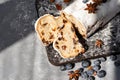 Sliced Christstollen cutted on pieces with raisins and blueberry on wooden board, aesthetic sunlight shadows on gray