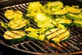 sliced courgettes in a grill basket over barbecue flames
