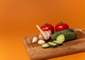 Sliced cucumber, tomatoes and garlic on wooden cutting board. Tomatoes with green ponytails. Healthy food. Copy space Royalty Free Stock Photo