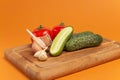 Sliced cucumber, tomatoes and garlic on wooden cutting board. Tomatoes with green ponytails. Healthy food. Copy space Royalty Free Stock Photo