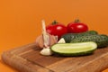 Sliced cucumber, tomatoes and garlic on wooden cutting board. Tomatoes with green ponytails. Healthy food. Copy space. High Royalty Free Stock Photo