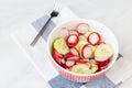 Sliced cucumer and red radishes in salad with fork on the table