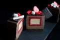 Sliced dark chocolate textured cube dessert with strawberry and vanilla insertion decorations and red sponge