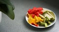 Sliced and diced exotic fruits served on a plate, with a plant in background Royalty Free Stock Photo