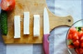 Sliced feta cheese cheese on a wooden board with vegetables and a knife Royalty Free Stock Photo