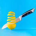 Sliced floating fresh lemon and a knife on a blue background