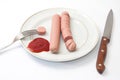 Sliced frankfurters on the plate with ketchup and spoon and fork
