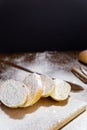 Sliced French baguette on a wooden board  cinnamon sticks and a large spoonful  heavily floured on a wooden table with Royalty Free Stock Photo