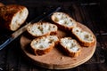 Sliced French baguette on a wooden board on a dark background. Bread with big holes. Preparing for bruschetta Royalty Free Stock Photo