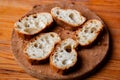 Sliced French baguette on a wooden board on a light background. Bread with big holes. Preparing for bruschetta Royalty Free Stock Photo