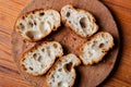 Sliced French baguette on a wooden board on a light background. Bread with big holes. Preparing for bruschetta Royalty Free Stock Photo