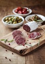 Sliced french salami with fresh rosemary and olives on rustic wooden background. Royalty Free Stock Photo