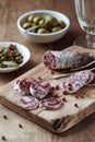 Sliced french salami with fresh rosemary and olives on rustic wooden background. Royalty Free Stock Photo