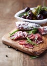 Sliced french salami with fresh rosemary on rustic wooden background. Royalty Free Stock Photo