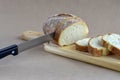 Sliced fresh bread loaf and knife on cutting board. Baked bread lies on table on craft paper home baked loaf.