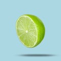 Sliced fresh juicy lime in air on light blue background. Citrus fruit Royalty Free Stock Photo