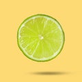 Sliced fresh juicy lime in air on light orange background. Citrus fruit Royalty Free Stock Photo