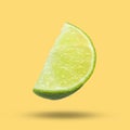 Sliced fresh juicy lime in air on light orange background. Citrus fruit Royalty Free Stock Photo