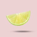 Sliced fresh juicy lime in air on light pink background. Citrus fruit Royalty Free Stock Photo