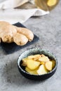 Sliced fresh raw ginger root in a bowl on the table. Alternative medicine. Vertical view