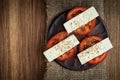 sliced fresh tomatoes under soft cheese with mediterranean spices on a clay plate on a burlap napkin on an old textured wooden Royalty Free Stock Photo
