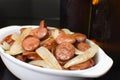 Sliced and fried Calabrese sausage with onions close with two bottle of beers in the background