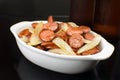 Sliced and fried Calabrese sausage with onions with two bottle of beers in the background