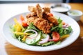 sliced fried chicken atop a fresh salad