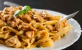 Sliced fried chicken breast meat in a creamy sauce with bavette pasta in a plate