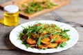 Sliced fried potatoes with arugula and spices on a white plate