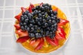 Sliced fruit - apples, oranges, kiwi topped with grapes on white dish Royalty Free Stock Photo