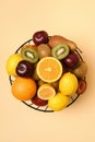 Sliced ??fruit in a metal basket. View from above. Place for text. Apples, bananas, oranges, kiwi, plums.