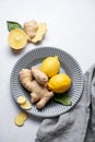 Sliced ginger root and lemon on a ceramic plate on a light textured background with napkin Royalty Free Stock Photo